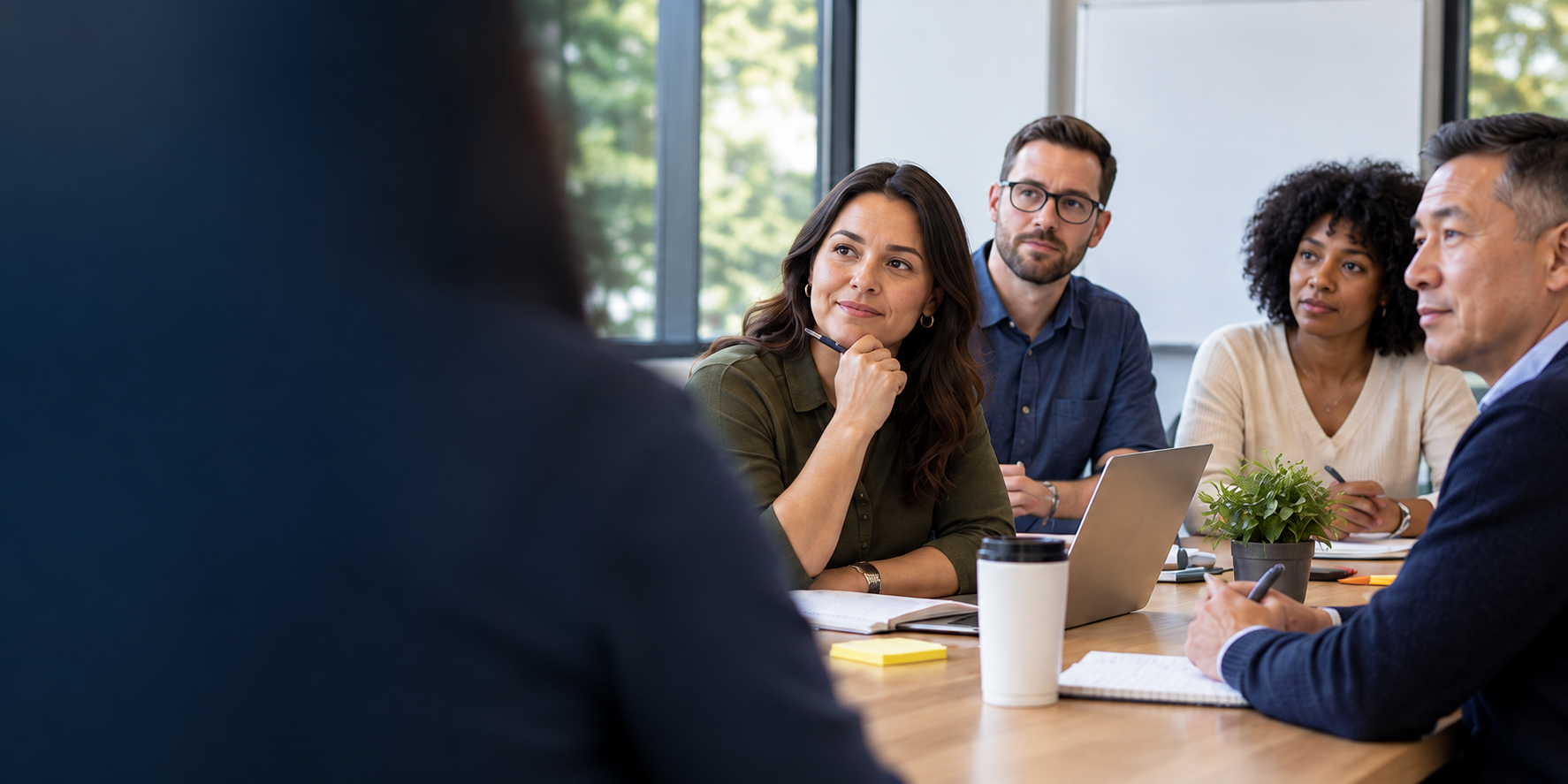 Illustrative corporate training scene: adults gathered around a conference table with course materials.
